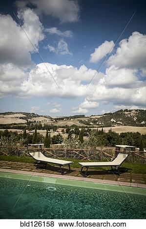 Lawn chairs by pool in rural landscape View Large Photo Image Stock Photo - Lawn chairs by pool in rural landscape. Fotosearch