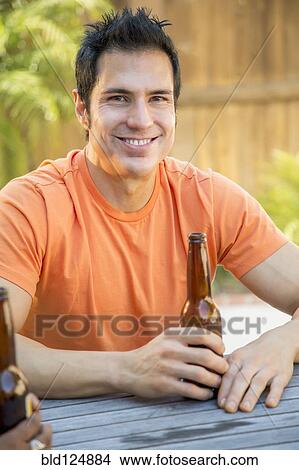 Picture - Man drinking beer in backyard. Fotosearch