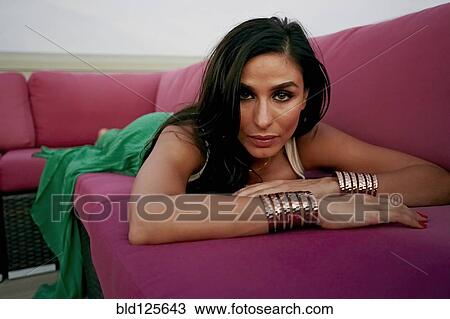 Stock Image - Middle Eastern woman laying on sofa. Fotosearch
