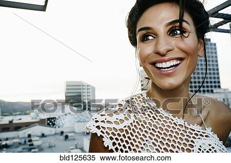 Stock Photography - Middle Eastern woman smiling on urban rooftop. Fotosearch