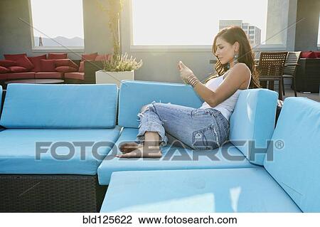 Middle Eastern woman using cell phone on sofa View Large Photo Image Stock Image - Middle Eastern woman using cell phone on sofa. Fotosearch