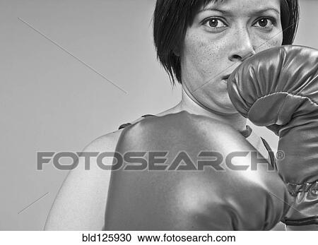 Stock Image - Mixed race boxer holding gloves in front of face. Fotosearch
