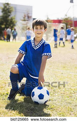 Mixed race boy with soccer ball kneeling on field View Large Photo Image Stock Photography - Mixed race boy with soccer ball kneeling on field. Fotosearch