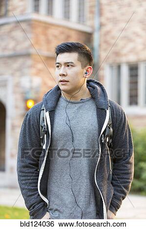 Stock Photograph - Mixed race college student listening to music on headphones. Fotosearch