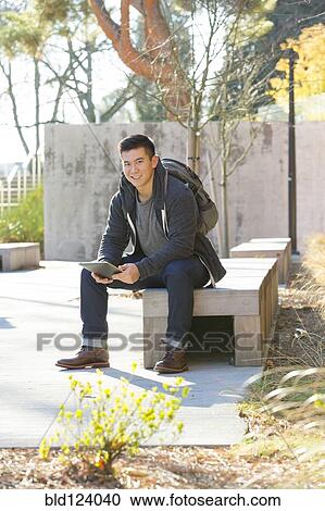 Mixed race college student using digital tablet on campus View Large Photo Image Stock Image - Mixed race college student using digital tablet on campus. Fotosearch