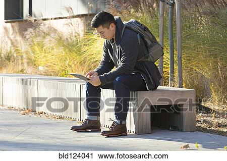 Mixed race college student using digital tablet on campus View Large Photo Image Stock Image - Mixed race college student using digital tablet on campus. Fotosearch
