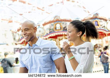 Stock Image - Mixed race couple laughing at amusement park. Fotosearch