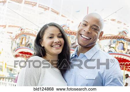 Stock Photo - Mixed race couple smiling at amusement park. Fotosearch