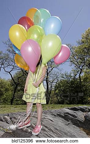 Mixed race girl carrying colorful balloons in park View Large Photo Image Stock Photograph - Mixed race girl carrying colorful balloons in park. Fotosearch