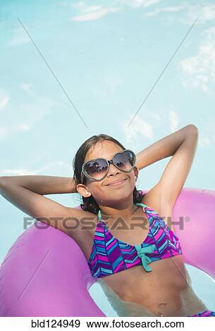 Mixed race girl floating in swimming pool View Large Photo Image Stock Photo - Mixed race girl floating in swimming pool. Fotosearch