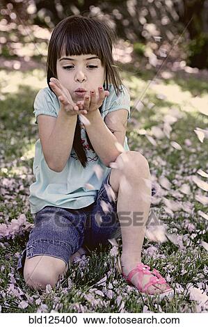 Stock Image - Mixed race girl playing with flowers in park. Fotosearch