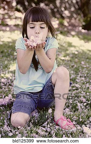 Mixed race girl playing with flowers in park View Large Photo Image Stock Photo - Mixed race girl playing with flowers in park. Fotosearch