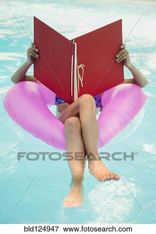 Stock Photo - Mixed race girl reading in swimming pool. Fotosearch