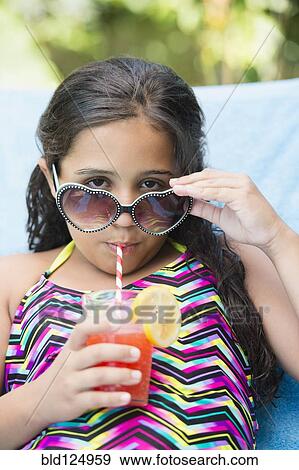 Stock Photo - Mixed race girl sipping juice at poolside. Fotosearch