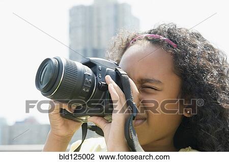Stock Image - Mixed race girl taking pictures outdoors. Fotosearch