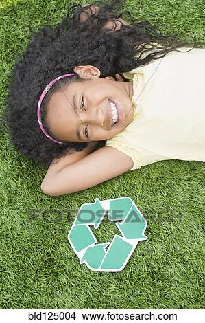 Picture - Mixed race girl with recycle symbol in grass. Fotosearch