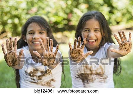 Stock Image - Mixed race girls covered in mud outdoors. Fotosearch