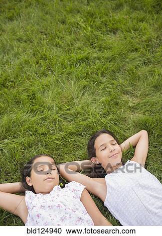 Mixed race girls laying in grass View Large Photo Image Stock Image - Mixed race girls laying in grass. Fotosearch