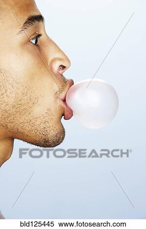Stock Photography - Mixed race man blowing bubble with gum. Fotosearch