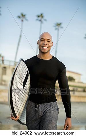 Mixed race man carrying surfboard on beach View Large Photo Image Stock Image - Mixed race man carrying surfboard on beach. Fotosearch