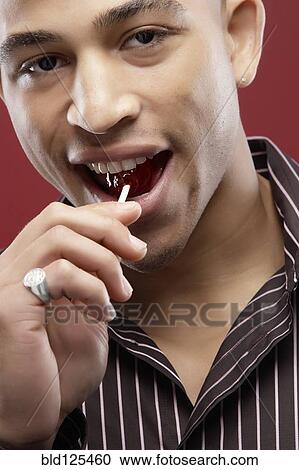 Mixed race man eating lollipop View Large Photo Image Stock Image - Mixed race man eating lollipop. Fotosearch