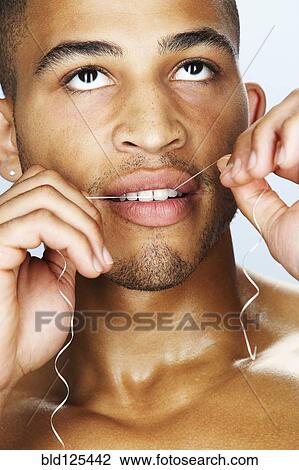 Mixed race man flossing his teeth View Large Photo Image Stock Image - Mixed race man flossing his teeth. Fotosearch