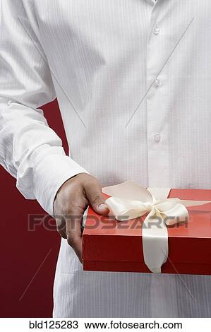Stock Image - Mixed race man holding wrapped gift. Fotosearch