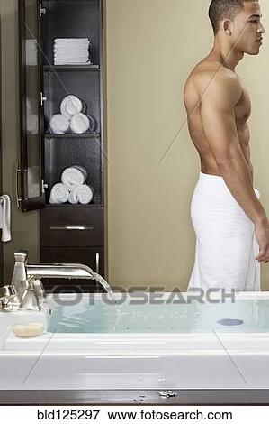 Stock Photo - Mixed race man running bath. Fotosearch