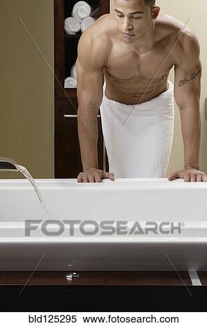 Stock Photography - Mixed race man running bath. Fotosearch