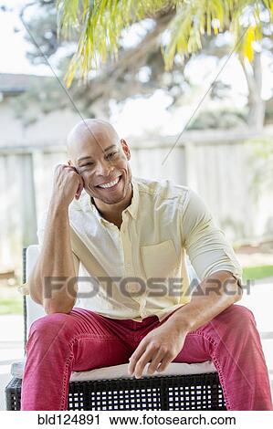 Stock Image - Mixed race man smiling in backyard. Fotosearch