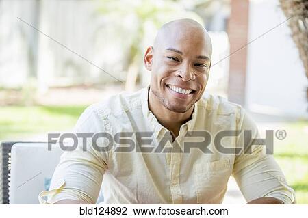 Stock Image - Mixed race man smiling in backyard. Fotosearch