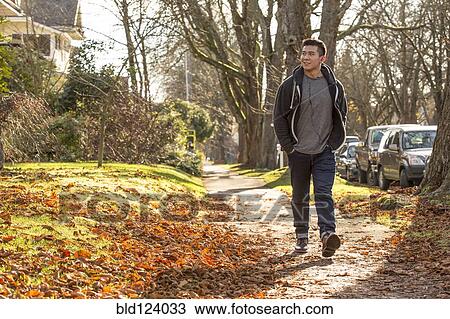 Mixed race man walking on suburban street View Large Photo Image Stock Image - Mixed race man walking on suburban street. Fotosearch