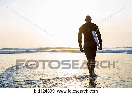 Mixed race man walking with surfboard on beach View Large Photo Image Stock Photo - Mixed race man walking with surfboard on beach. Fotosearch