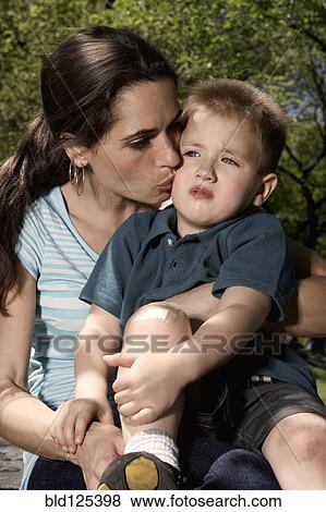 Mixed race mother kissing hurt son in park View Large Photo Image Stock Photo - Mixed race mother kissing hurt son in park. Fotosearch