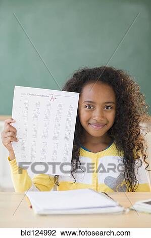 Stock Image - Mixed race student showing off A plus grade in classroom. Fotosearch