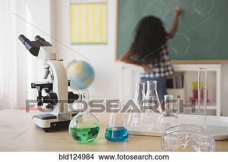 Picture - Mixed race student writing on chalkboard in classroom. Fotosearch
