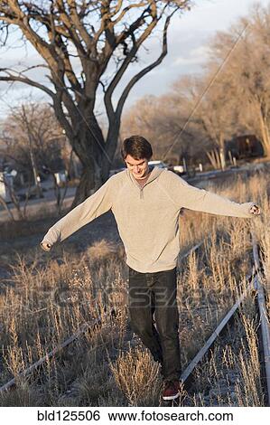 Stock Photograph - Mixed race teenage boy walking on train tracks. Fotosearch