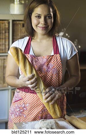 Stock Image - Mixed race woman baking bread in kitchen. Fotosearch
