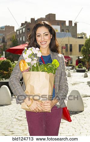 Mixed race woman carrying shopping bag on city street View Large Photo Image Stock Image - Mixed race woman carrying shopping bag on city street. Fotosearch