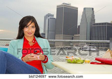 Mixed race woman eating lunch by urban river, New York, New York, United States View Large Photo Image Stock Photo - Mixed race woman eating lunch by urban river, New York, New York, United States. Fotosearch