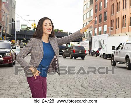 Stock Photo - Mixed race woman hailing taxi on city street. Fotosearch