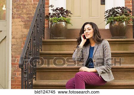 Mixed race woman on cell phone on front stoop View Large Photo Image Stock Photography - Mixed race woman on cell phone on front stoop. Fotosearch