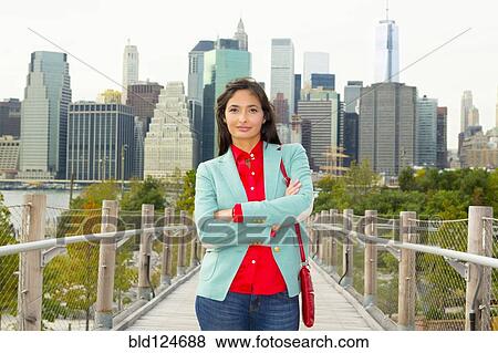 Stock Photo - Mixed race woman on footbridge in front of city skyline, New York, New York, United States. Fotosearch