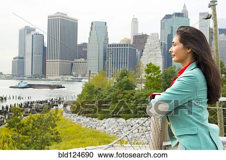 Stock Image - Mixed race woman overlooking park and river, New York, New York, United States. Fotosearch