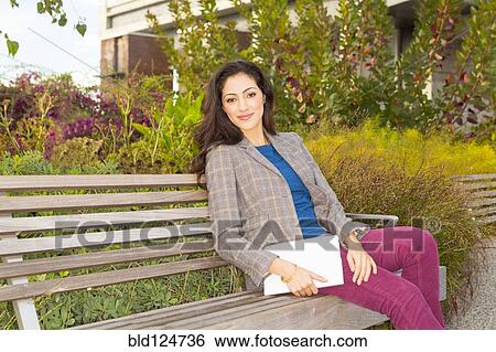 Mixed race woman sitting on park bench View Large Photo Image Stock Photograph - Mixed race woman sitting on park bench. Fotosearch