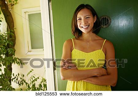 Stock Image - Mixed race woman smiling at front door. Fotosearch
