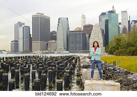 Stock Image - Mixed race woman smiling at urban waterfront, New York, New York, United States. Fotosearch