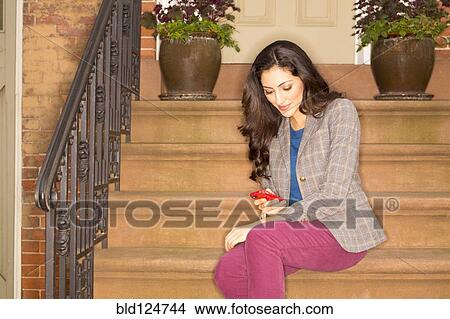 Mixed race woman using cell phone on front stoop View Large Photo Image Picture - Mixed race woman using cell phone on front stoop. Fotosearch