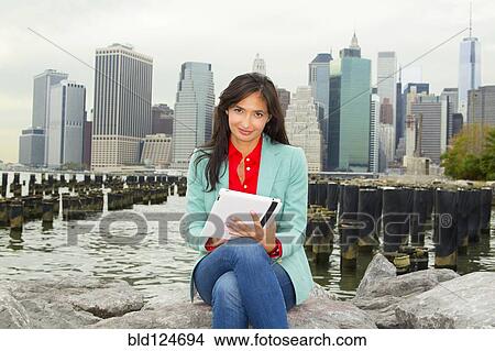 Mixed race woman using digital tablet by urban harbor View Large Photo Image Picture - Mixed race woman using digital tablet by urban harbor. Fotosearch