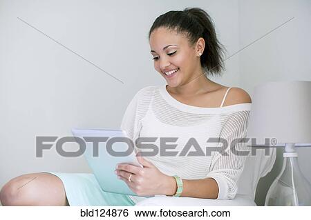 Stock Photograph - Mixed race woman using digital tablet. Fotosearch